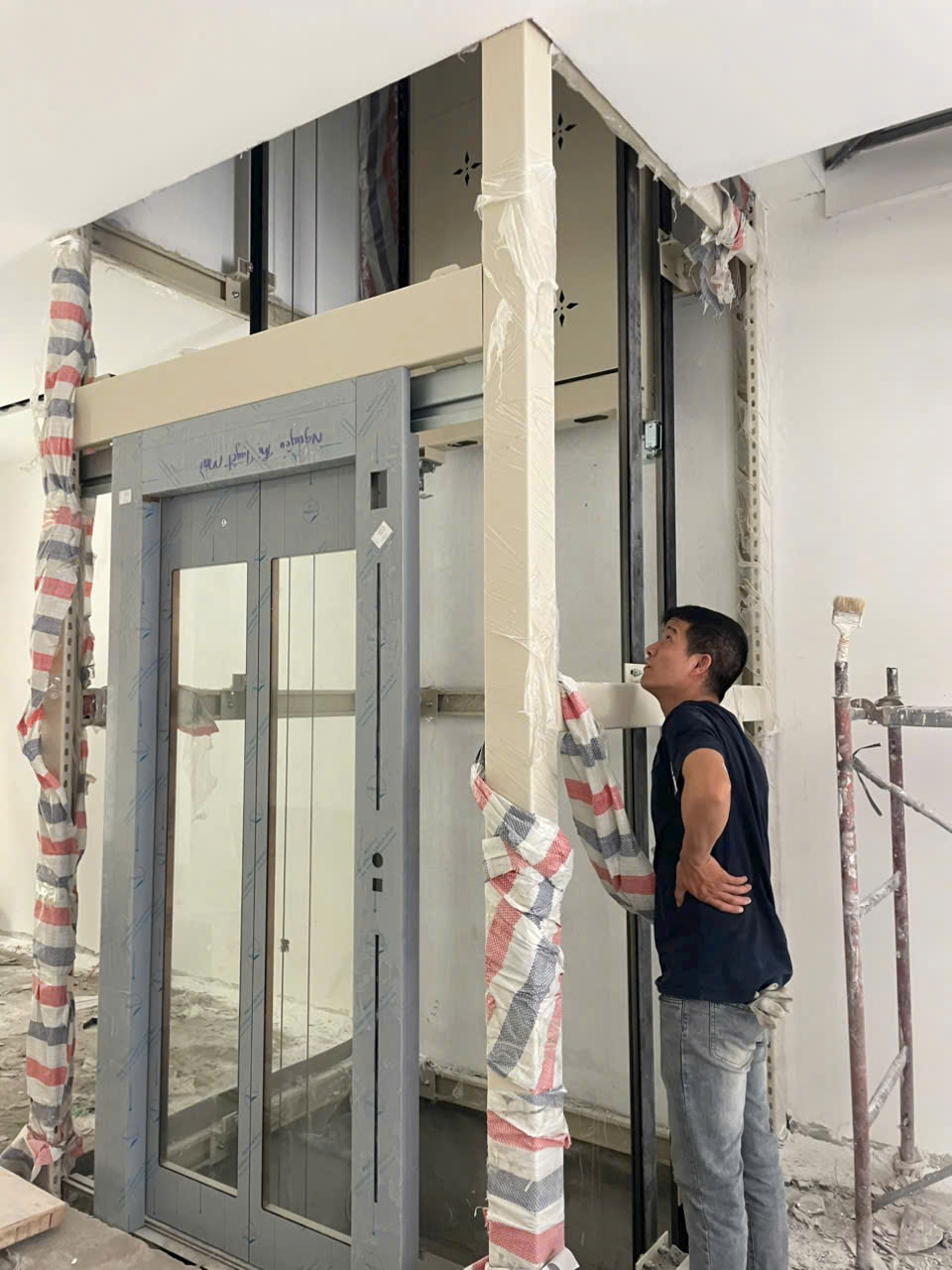 Thợ kỹ thuật đang lắp đặt thang máy gia đình khung thép trong nhà đang xây dựng